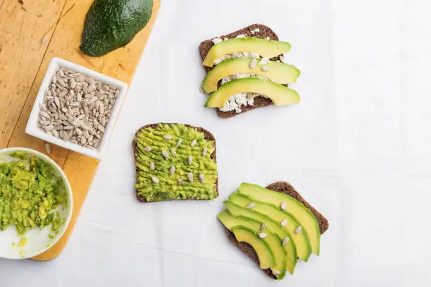 Three avocado toast breakfast with sunflower seeds and rye bread. Top view