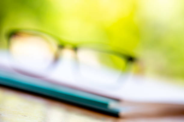 istock Blurred black eyeglasses with three white notebooks on wooden table, Bokeh garden background, Close up & Macro shot, Stationery concept 1133510630