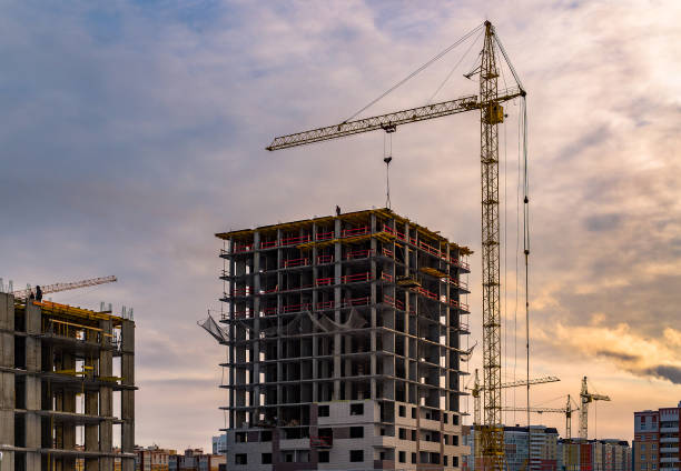 istock Building crane and building under construction. Construction site. Construction cranes and high rise building under construction against cloudy sky 1133511916