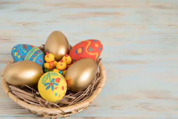 Gold Easter eggs in a basket with yellow baby chicken Easter conceptual picture with copyspace