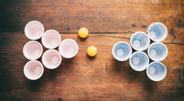 Beer pong. Plastic red and blue color cups and ping pong balls on wood, top view Beer pong, college party game. Plastic red and blue color cups and ping pong balls on wooden background, top view pub table top view stock pictures, royalty-free photos & images