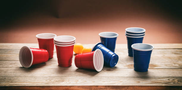 Beer pong. Plastic red and blue color cups and ping pong balls on wood, banner Beer pong, college party game. Plastic red and blue color cups and ping pong balls on wooden background, banner red party cup stock pictures, royalty-free photos & images