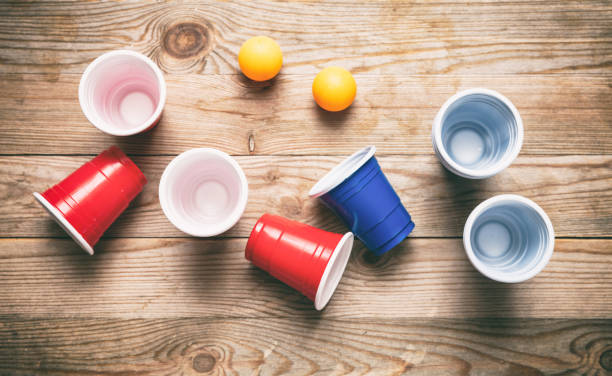 bière pong. tasses en plastique rouge et bleu de couleur et boules de ping-pong sur le bois, vue de dessus - disposable cup red beer plastic photos et images de collection