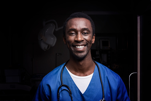 Portrait of smiling male nurse with stethoscope. Confident healthcare worker is working in hospital. He is wearing scrubs.
