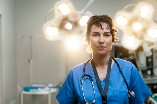 Portrait of confident female surgeon in hospital Portrait of confident female surgeon. Healthcare worker is against illuminated lights in hospital. She is having short hair. surgeon stock pictures, royalty-free photos & images