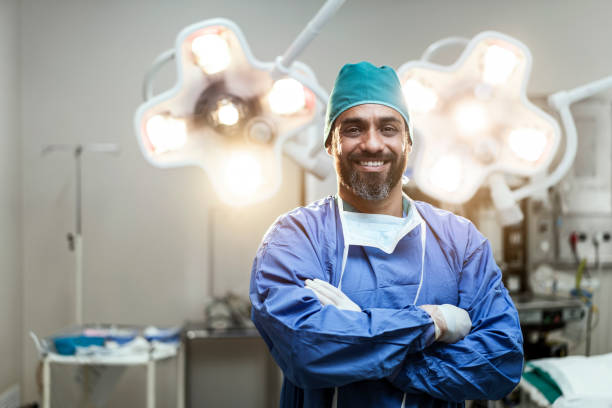 porträt des lächelnden männlichen chirurgen mit gekreuzten armen - chirurg stock-fotos und bilder