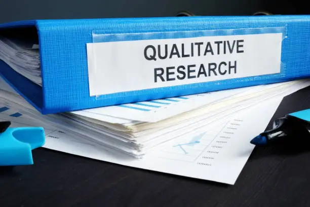 Photo of Qualitative research methods report in a blue folder.