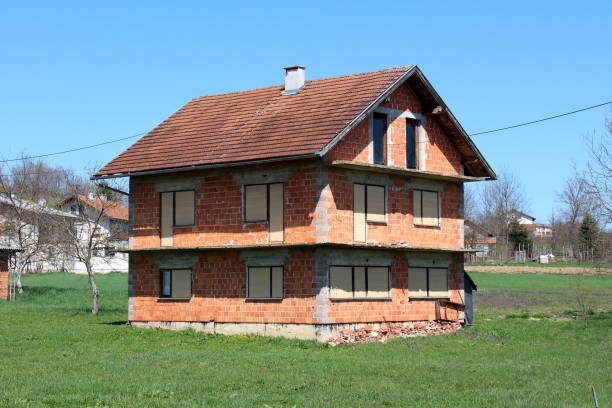 istock Abandoned unfinished red brick house with completely closed window blinds surrounded with uncut grass and family houses in back 1133523084
