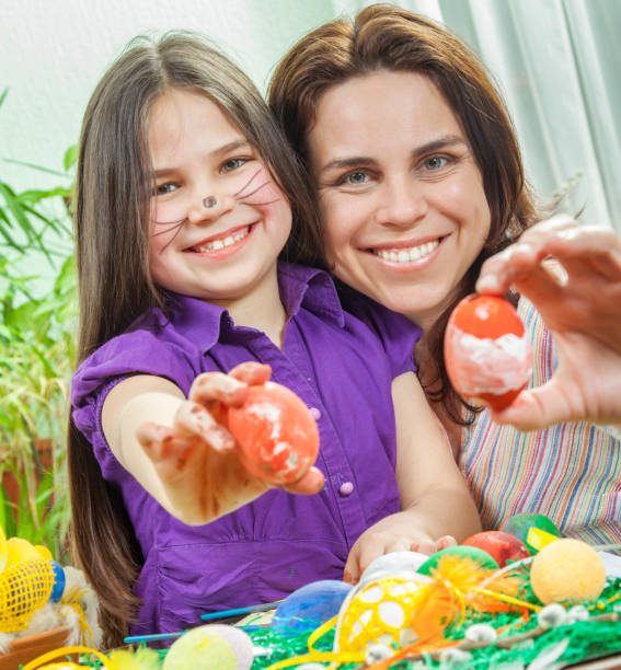 istock Mother showing to her children how to paint  Easter eggs 1133524964