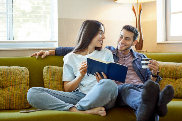 istock Smiling girlfriend showing diary to male on sofa 1133527341