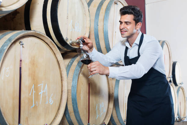 istock Man pouring red wine into glass in alcohol section 1133527435