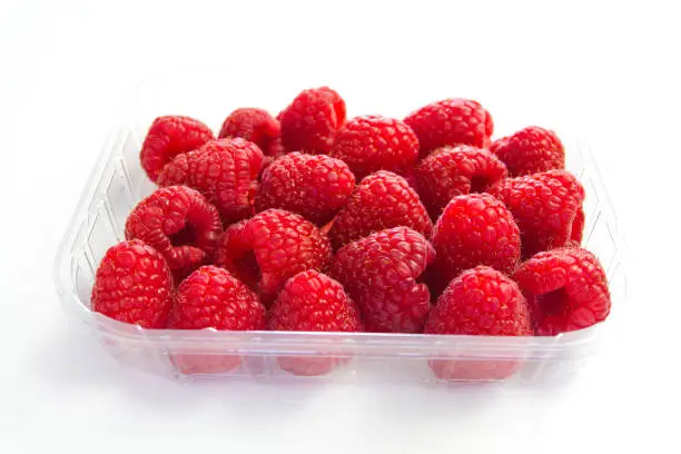 tray of fresh raspberries isolated on a white background