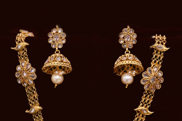 istock Fancy Designer golden earrings closeup macro image on red background 1133528035