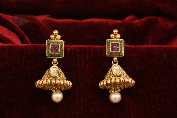 istock Fancy Designer golden earrings closeup macro image on red background 1133528069