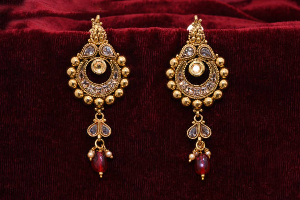 istock Fancy Designer golden earrings closeup macro image on red background 1133528684