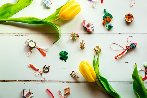 Color image depicting an overhead view of traditional Romanian martisor, little gifts given mainly to women and children on 1 March, the beginning of Spring, in Romania. The image is decorated with fresh yellow spring tulip flowers. Room for copy space.