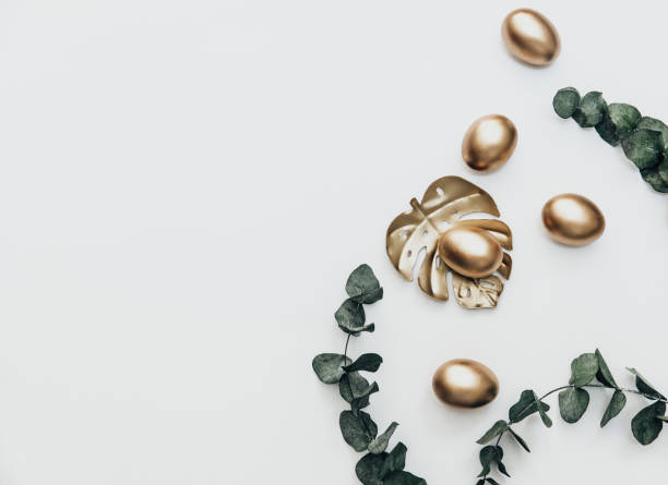 Minimal Flat lay Gold Easter eggs with eucalyptus  flower on white background. Top view, Still Life Happy Easter holiday concept