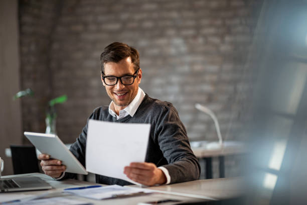 istock Happy businessman going through paperwork and using touchpad in the office. 1133529218