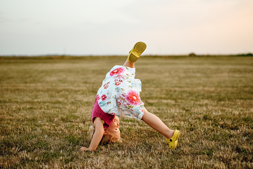 Young girl balancing doing a gymnastic move on rocks at Tighnabruaich in Argyll and Bute UK