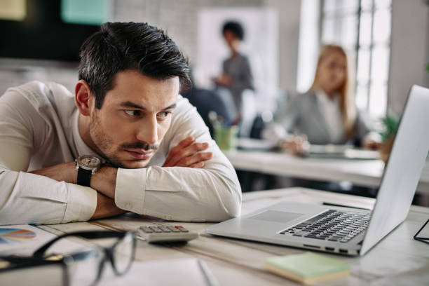 istock Bored businessman reading e-mail on laptop while working in the office. 1133530413