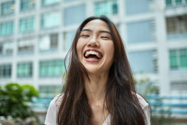 Portrait of smiling young woman at city Close-up of cheerful young woman. Portrait of beautiful happy female with long hair. She is in casuals at city. chinese woman stock pictures, royalty-free photos & images