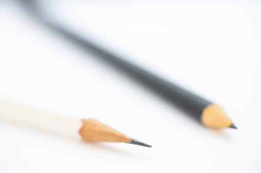 A white pencil with a black pencil on white background, Close up & Macro shot, Selective focus, Stationery concept