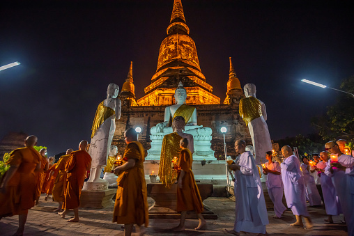Ayutthaya ,Thailand - February 19, 2019 : Buddhists people walking (motion blur)  with lighted candles in hand around a ancient temple on Magha Puja day at Ayutthaya province of Thailand.