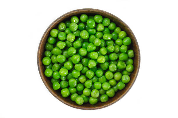 istock green peas on wooden bowl on white background. 1133540398