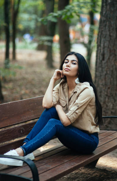 istock Beautiful young girl sitting on a park bench 1133543499