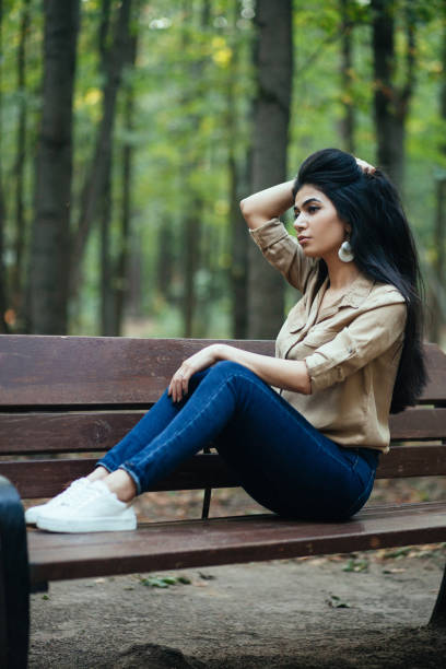 istock Beautiful young girl sitting on a park bench 1133543665