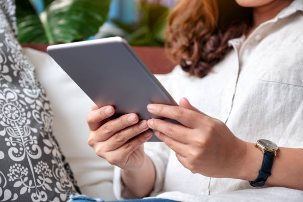 istock Closeup image of a beautiful asian woman holding and using tablet pc while sitting on sofa 1133543912