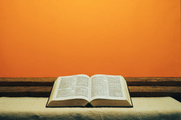 istock Open Bible on a old table. Beautiful yellow wall background. Religion concept. 1133546887