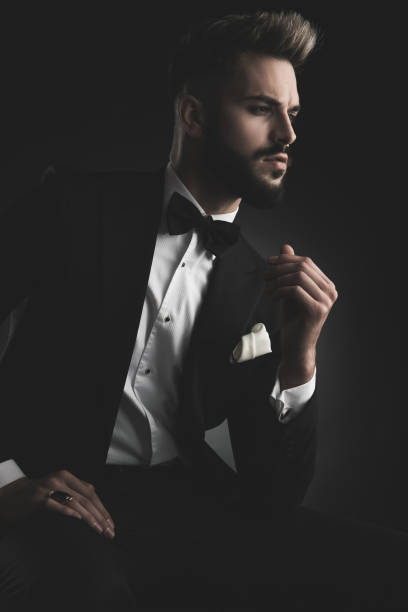 istock man in tuxedo holding his hand on foot 1133546910