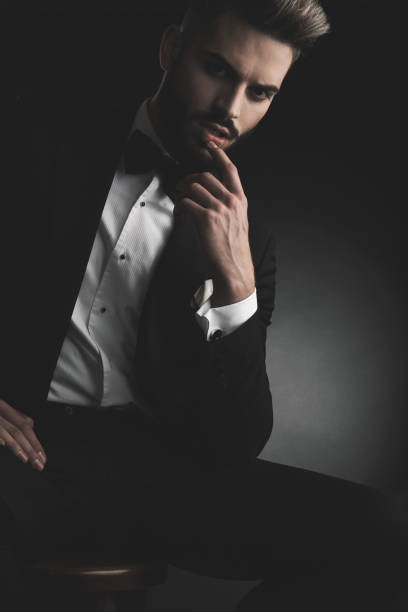 istock man in tuxedo sitting on chair with finger at lips 1133547092