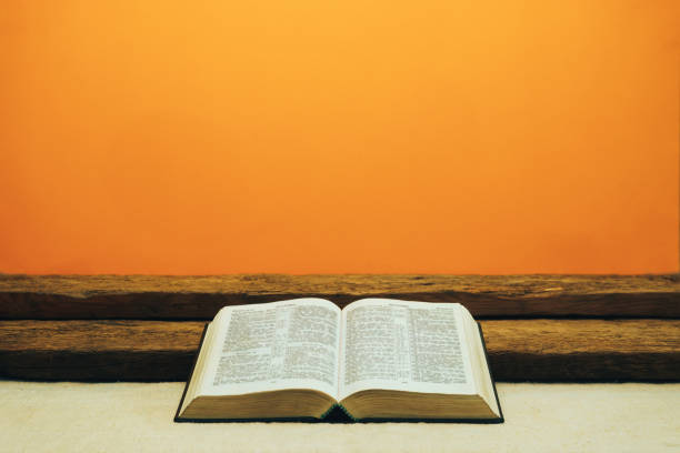 istock Open Bible on a old table. Beautiful yellow wall background. Religion concept. 1133547122