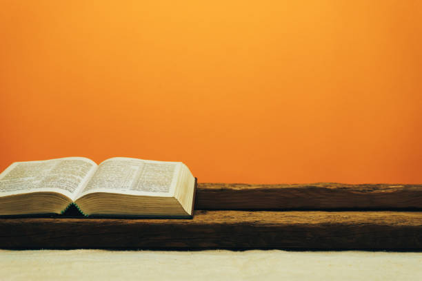 istock Open Bible on a old table. Beautiful yellow wall background. Religion concept. 1133547137