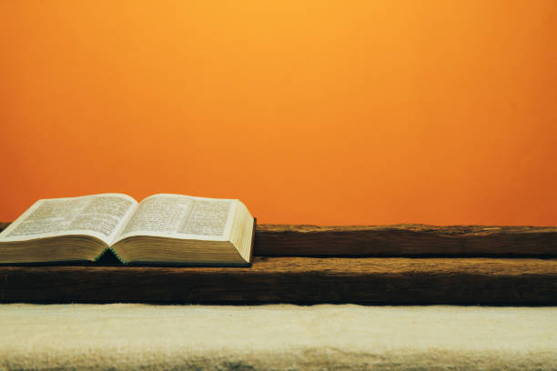 istock Open Bible on a old table. Beautiful yellow wall background. Religion concept. 1133547147