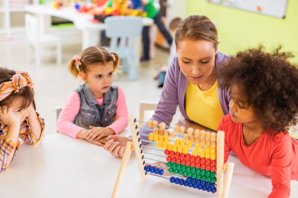 istock Happy teacher and kids learning to count on abacus at preschool. 1133549921