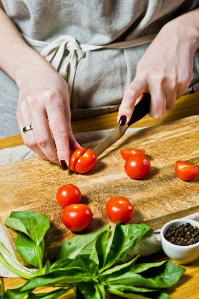 istock The chef cuts cherry tomatoes on a wooden chopping Board. Black background, side view, space for text. 1133550530
