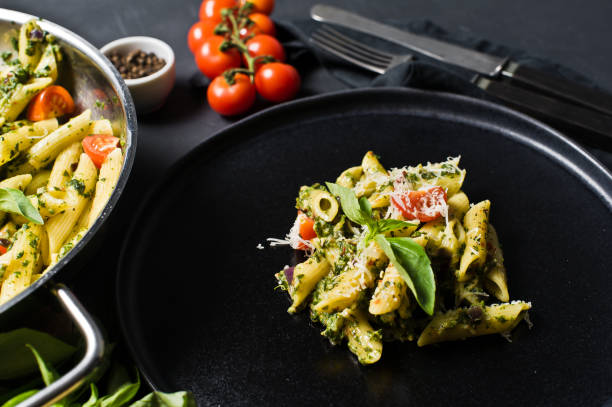 istock Pasta Penne with spinach, cherry tomatoes, Basil and Parmesan. Black background, side view. 1133551398