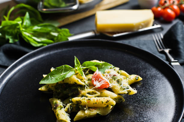 istock Italian pasta Penne with spinach, cherry tomatoes and Basil. Black background, side view. 1133551419