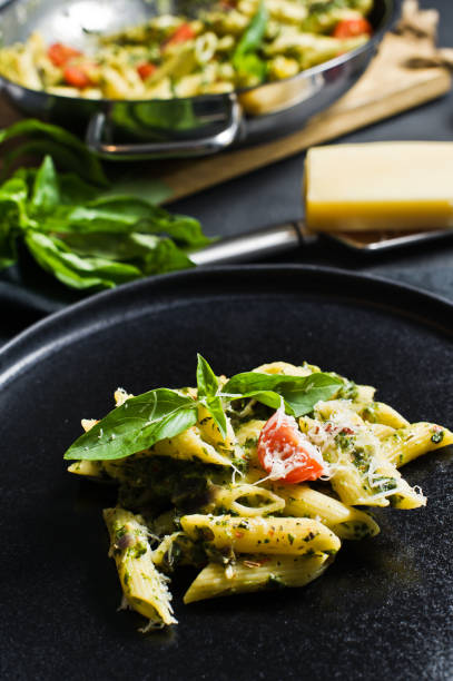 istock Italian pasta Penne with spinach, cherry tomatoes and Basil. Black background, side view. 1133551420