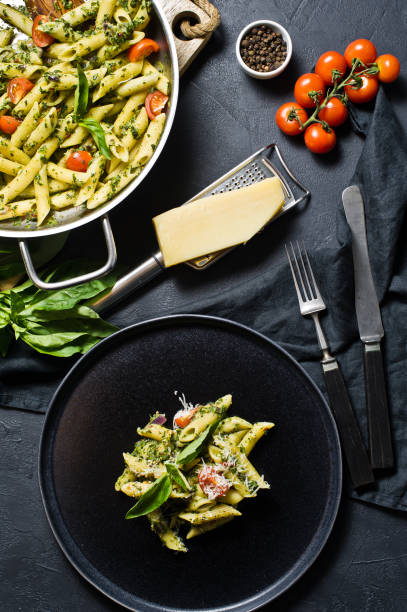 istock Italian pasta Penne with spinach, cherry tomatoes and Basil. Black background, top view. 1133551421