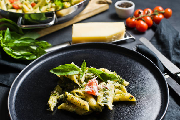 istock Pasta Penne with spinach, cherry tomatoes, Basil and Parmesan. Black background, side view. 1133551434
