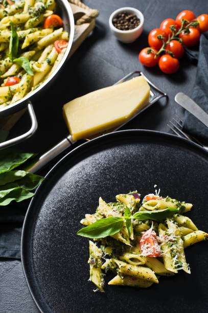 istock Pasta Penne with spinach, cherry tomatoes, Basil and Parmesan. Black background, side view. 1133551439
