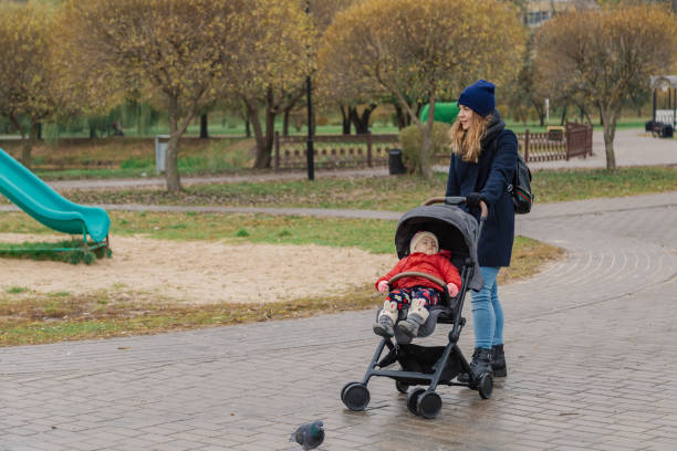 istock A woman walks in the park with a stroller and a small child 1133553105