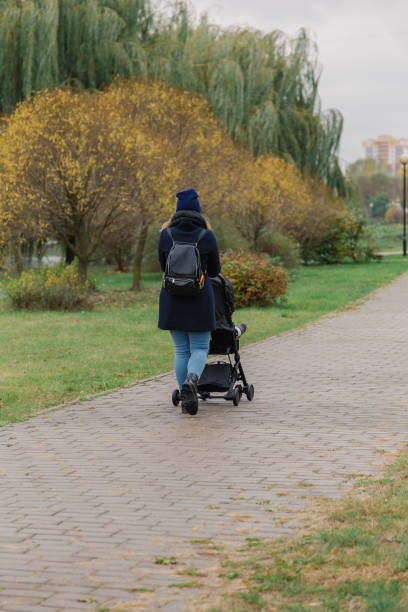 istock A woman walks in the park with a stroller and a small child 1133553600
