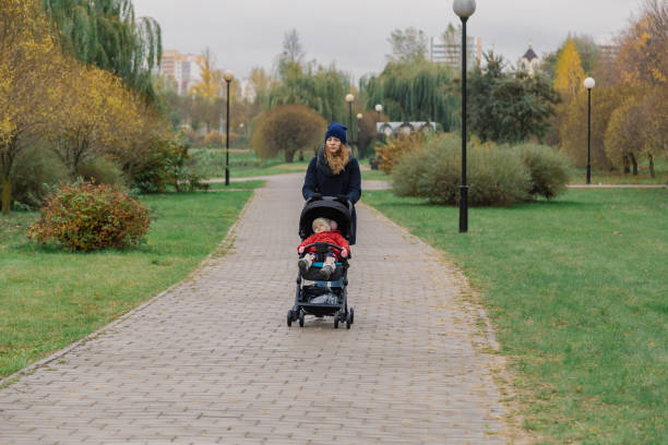 istock A woman walks in the park with a stroller and a small child 1133553694