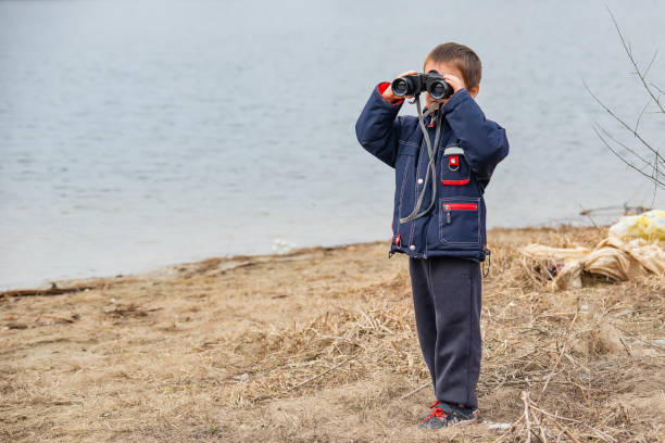 istock Little boy looking through binoculars on river bank 1133558206