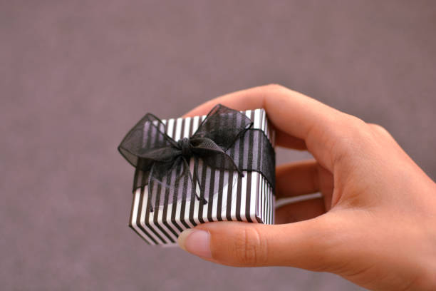 istock Female hand holding a small gift box on violet background 1133559902